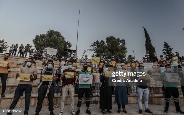 People hold banners as they stage a protest against 2013 Eastern Ghouta chemical attack of Assad regime forces, in Idlib, Syria on August 21, 2020....