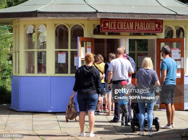 People queue at an ice cream parlour. Museums re-opened in the UK with protective face masks required indoors. With face masks already mandatory on...