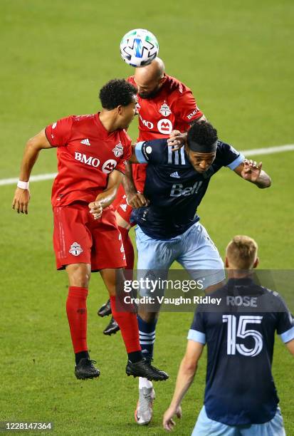 Laurent Ciman and Justin Morrow of Toronto FC battle for a header with Derek Cornelius of Vancouver Whitecaps FC during the second half of an MLS...