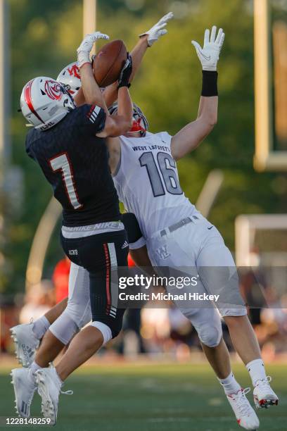 Caleb Koeppen of the Lafayette Jefferson Broncos goes up for a pass against Cannon Melchi and Sam Schott of the West Lafayette Red Devils at...