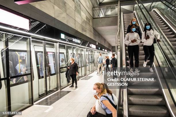 People wear mask at a metro station in Copenhagen shortly after midnight, on August 22 as the Danish government imposed to wear face mask or visor in...