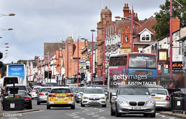 Police vehicles join Saturday morning traffic on Soho Road in the Handsworth area of Birmingham, central England on August 22 as Britain's...