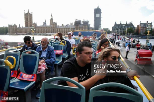 Tourists take pictures as they cross Westminster Bridge on a sightseeing bus on August 22, 2020 in London, England. Whilst the UK is open for...