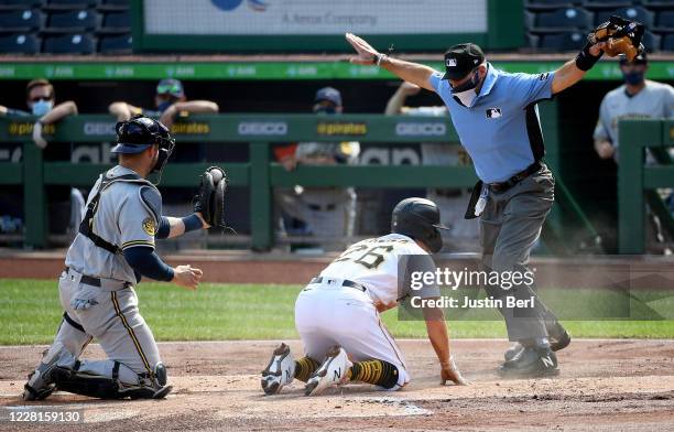 Umpire Angel Hernandez calls Adam Frazier of the Pittsburgh Pirates safe after a play at the plate against Manny Pina of the Milwaukee Brewers in the...