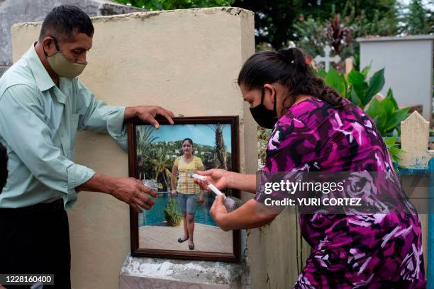Salvadoran Mirna del Carmen Solorzano and her husband Miguel Angel Medrano light a candle as they visit the grave of their daughter Glenda, at the...