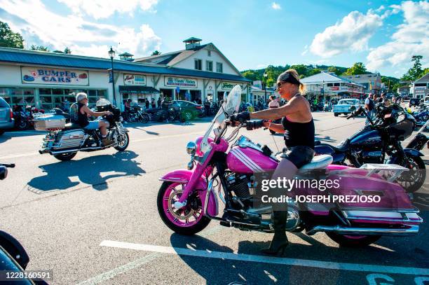 Woman on a pink motorcycle pulls out and onto the road along Lake Winnipesaukee at Weirs Beach during the 97th annual Laconia Bike Week in Laconia,...