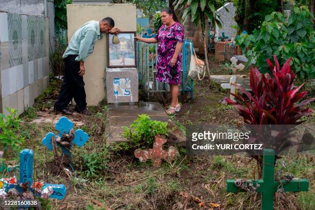 Salvadoran Mirna del Carmen Solorzano and her husband Miguel Angel Medrano visit the grave of their daughter Glenda, at the municipal cemetery in...