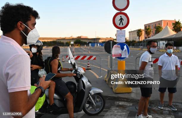 Holidaymakers returning from Sardinia by ferry, wait outside their vehicle to undergo a compulsory drive-through swab test on August 23, 2020 at the...