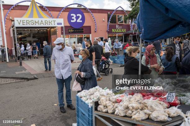 People wearing face masks walk in the Bazaar Beverwijk market, in Beverwijk, on August 23 after parts of the Bazaar have been closed by order of the...