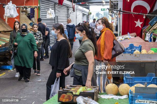 People wearing face masks walk in the Bazaar Beverwijk market, in Beverwijk, on August 23 after parts of the Bazaar have been closed by order of the...