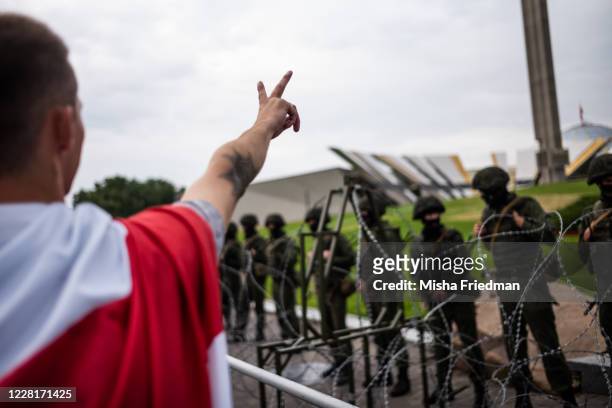 An anti-government protester gestures as he walks past riot police guarding the Belarusian State Museum of the History of the Great Patriotic War on...