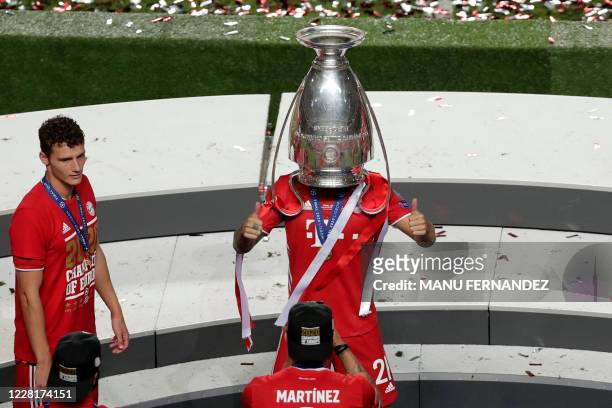 Bayern Munich's French defender Lucas Hernandez poses with the trophy upside down on his head next to Bayern Munich's French defender Benjamin Pavard...