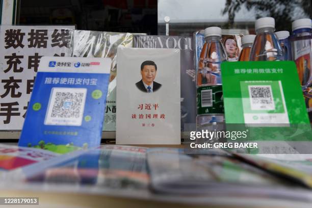 This photo taken on August 19, 2020 shows a book about Chinese President Xi Jinping, titled "Xi Jinping; The Governance of China", between QR payment...