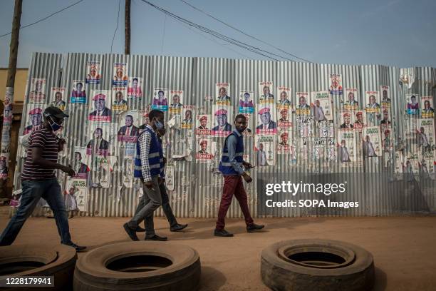 Men walk past election posters in Kampala. Uganda's elections are expected to take place early next year.