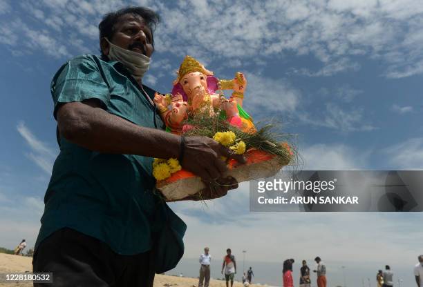 Devotee carries a clay idol of Hindu elephant-headed deity Ganesh for immersion on the third day of the Ganesh Chaturthi festival, in Chennai on...