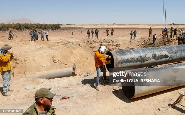 Syrian engineers repair a pipeline between the areas of Adra and al-Dhamir in the Damascus region on August 24 after it was reportedly a site of an...