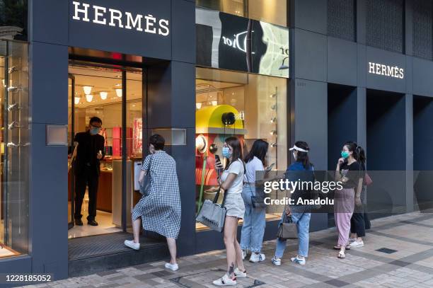 Shoppers queue in line to enter the French luxury fashion brand Hermes store in Tsim Sha Tsui, Hong Kong, China on August 24, 2020. Companies and the...