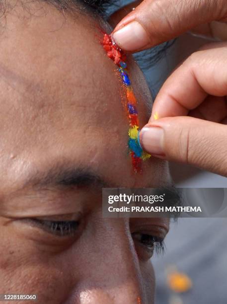 Nepalese women apply a seven-colour Tika - religious marking - to their brother's forehead on the occasion of Bhai Tika - brothers' worship - on the...