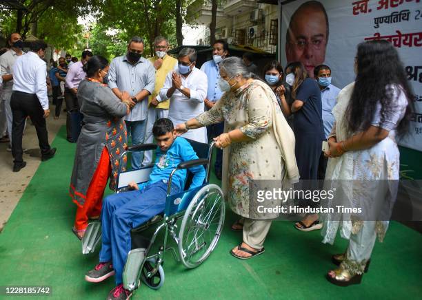 Family members of Arun Jaitely distribute wheel chair to a child with physical disabilities to mark his first death anniversary, at his residence at...