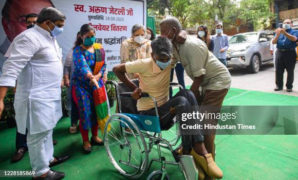 Family members of Arun Jaitely distribute wheel chair to a man with physical disabilities to mark his first death anniversary, at his residence at...