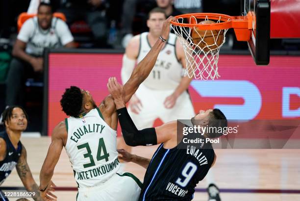Giannis Antetokounmpo of the Milwaukee Bucks dunks the ball over Nikola Vucevic of the Orlando Magic during the second half of an NBA basketball...