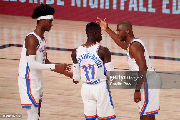 Chris Paul of the Oklahoma City Thunder talks with guard Shai Gilgeous-Alexander and Dennis Schroder during the first half of game four against the...