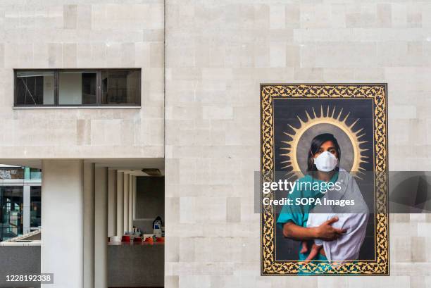 Artwork of a nurse wearing a face mask while holding a baby at the Everyday Heroes art installations in the outdoor spaces around the Hayward Gallery...