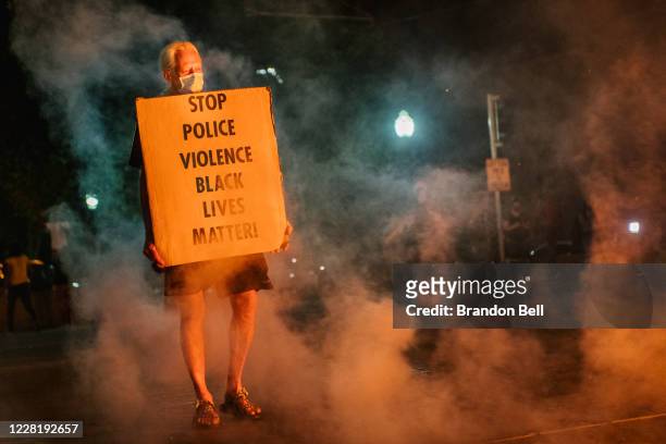 Man stands with a sign on August 24, 2020 in Kenosha, Wisconsin. This is the second night of rioting after the shooting of Jacob Blake on August 23....