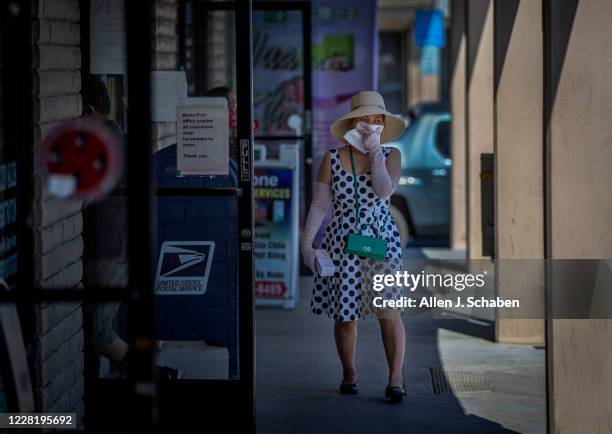 Woman holds a face covering over her mouth and nose in front of the U.S. Post Office in Little Saigon Wednesday, Aug. 5, 2020 in Westminster, CA. In...