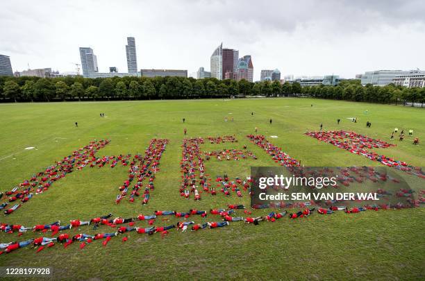 People lie on the grass in the Malieveld to form a message that reads 'help' during a protest in The Hague on August 25 to highlight the plight and...