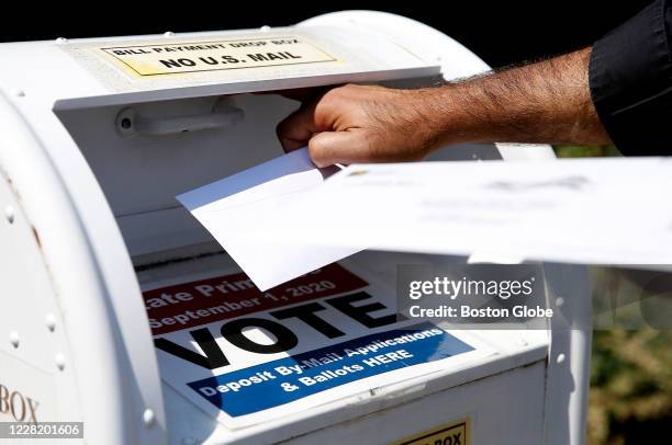 Voter drops a ballot into the box for mail-in ballots outside of Newton City Hall in Newton, MA on Aug. 23 where there's a crowded field in the...