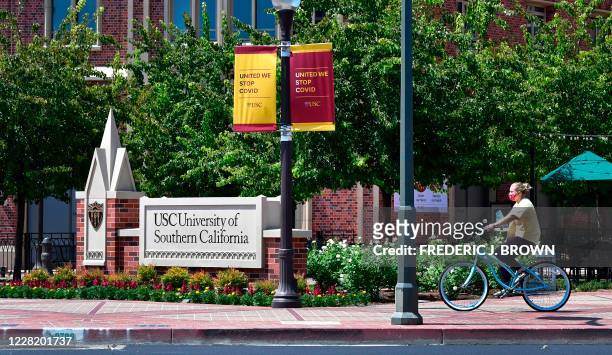 Cyclist wearing a facemask rides her bike at the University of Southern California in Los Angeles, California on August 25, 2020 where coronavirus...