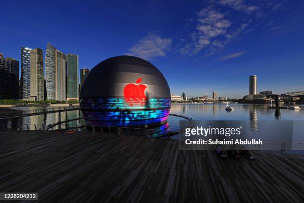Cyclists pose for a photo in front of the new Apple flagship store at Marina Bay Sands waterfront on August 26, 2020 in Singapore. The store located...