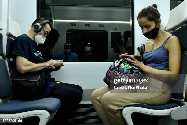 Passengers wearing protective masks handle electronic devices on the train of the Renfe company in Madrid, Spain, on August 17, 2020. People wearing...