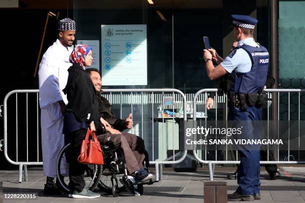 Police officer takes pictures for Nor Azila and her husband and survivor of the twin mosque shootings Rahimi Ahmad after the judgement and the last...