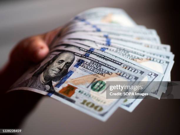 In this photo illustration one hundred US dollar banknotes are seen on display.