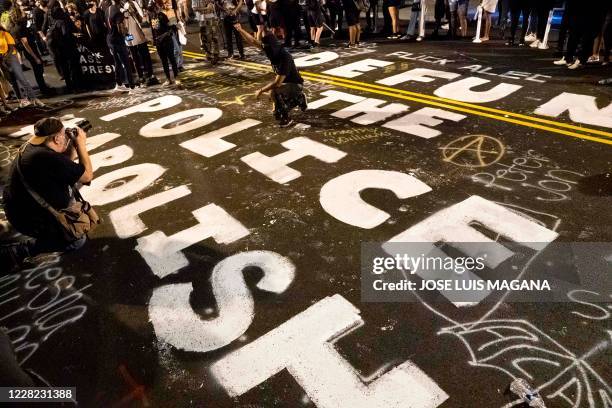 Demonstrators raise their fists around a mural dedicated to defund and abolish the police, during a rally to protest US President Donald Trump's...