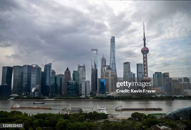 Boats travel on the Huangpu River as the skyline of the city is is seen, including the Oriental Pearl TV Tower and the Shanghai Tower, on August 28,...