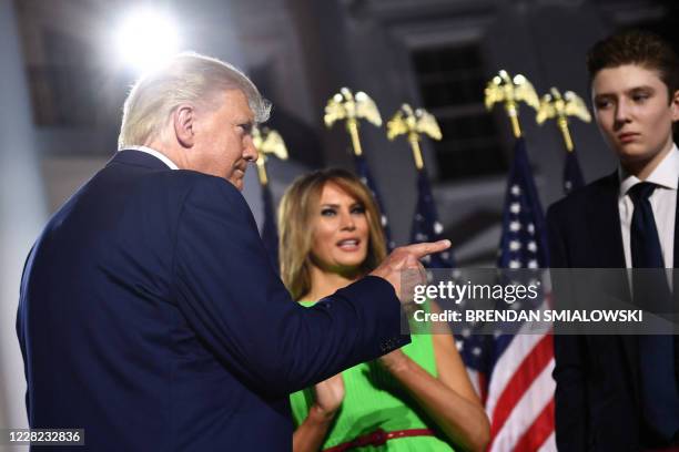 President Donald Trump gestures, flanked by First Lady Melania Trump and son Barron Trump, as they prepare to leave after he delivered his acceptance...