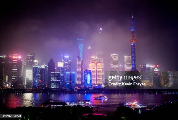 Boats travel on the Huangpu River as the skyline of the city is is seen in fog, including the Oriental Pearl TV Tower and the Shanghai Tower, on...