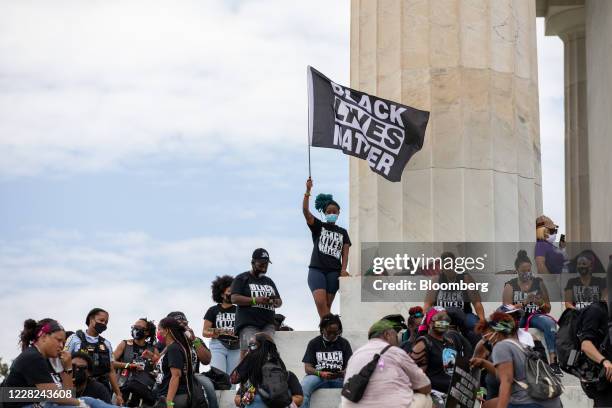 Demonstrator wearing a protective mask waves a "Black Lives Matter" flag on the steps of the Lincoln Memorial during the "Get Your Knee Off Our...