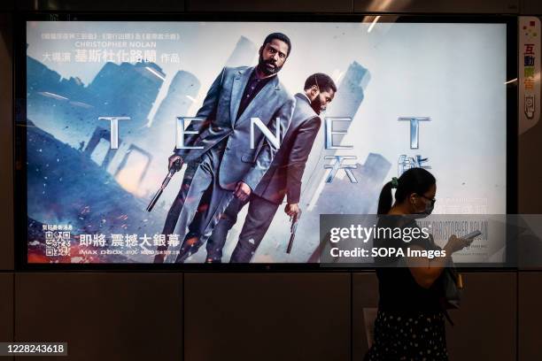 Commuter walks past a poster of Christopher Nolan's blockbuster film Tenet at MTR subway station in Hong Kong.
