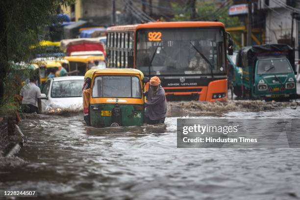 Commuters wade through a water-logged stretch of road following heavy rains, at Anand Parbat, on August 28, 2020 in New Delhi, India. Delhi NCR woke...