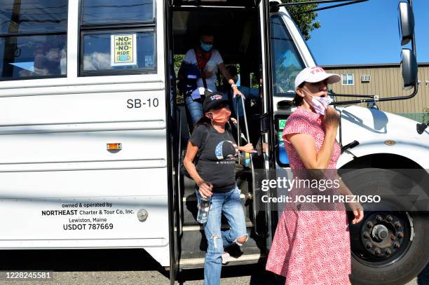 People unload from a shuttle bus, including a woman in a QAnon shirt, to get in line for the US President Donald Trump Campaign Rally, the day after...