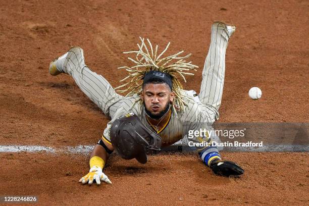 Fernando Tatis Jr. #42 of the San Diego Padres reacts after being hit by the ball on the pickoff attempt after sliding safely into third base with a...