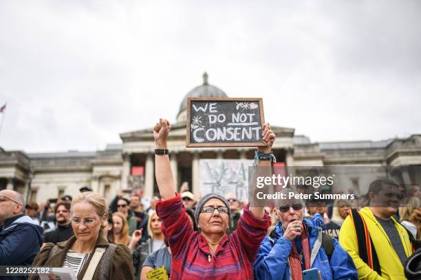 An anti-mask protester holds a sign reading 'We Do Not Consent' while a woman next to her coughs at the Unite for Freedom protest in Trafalgar Sq on...