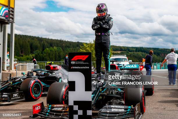 Mercedes' British driver Lewis Hamilton gestures in homage to late US actor Chadwick Boseman, as he stands on his car after securing his 93rd pole...