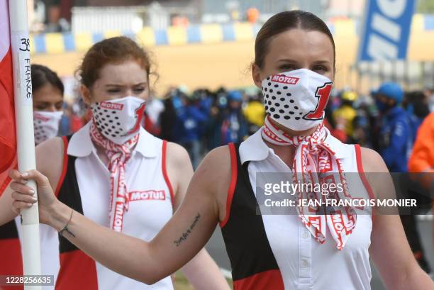 Grid girls wearing face masks hold flags on the starting grid prior to the 43rd Le Mans 24-hours endurance moto race in Le Mans, northwestern France,...