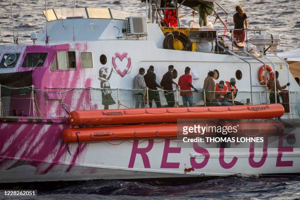 Migrants stand on the rescue ship funded by British street artist Banksy "Louise Michel" during a rescue operation by crew members of civil sea...