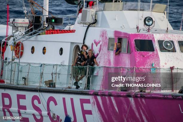 Crew members of rescue ship funded by British street artist Banksy "Louise Michel" wave during a rescue operation by crew members of civil sea rescue...